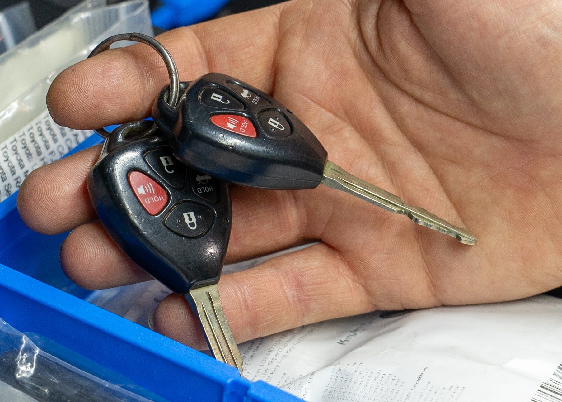 Two remote-head car keys on a key ring, resting in an open palm.